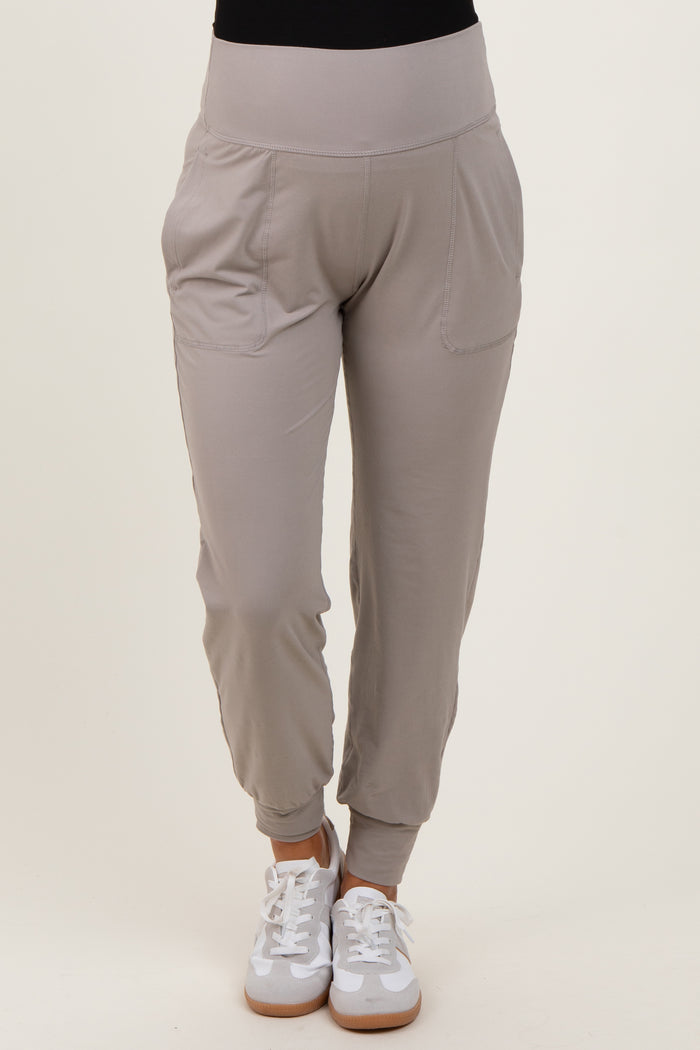 woman wearing light grey maternity jogger pants with side pockets and elastic waistband, paired with white sneakers