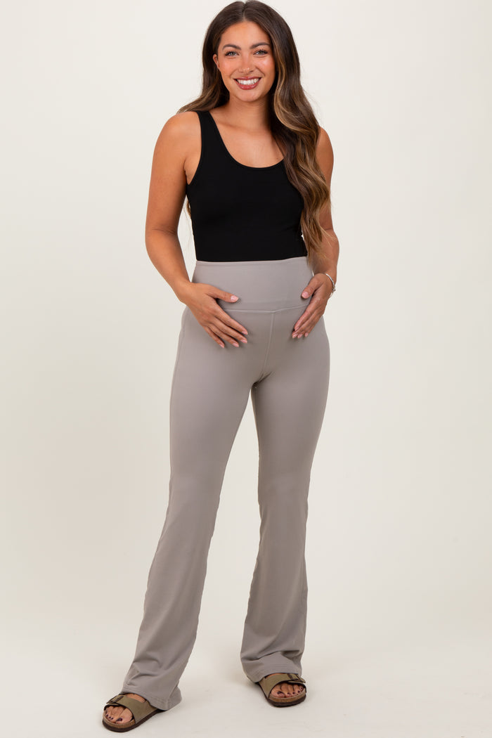 woman wearing a black tank top and beige maternity leggings, holding her baby bump