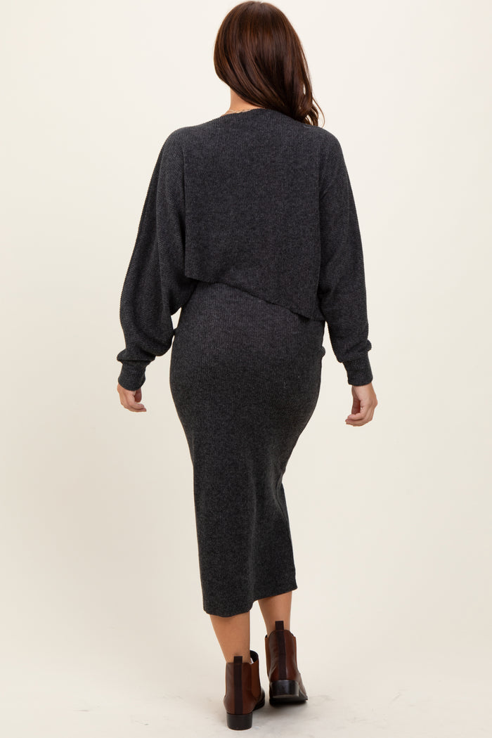 woman wearing a dark grey long sleeve fitted dress with a cropped sweater over it, seen from the back