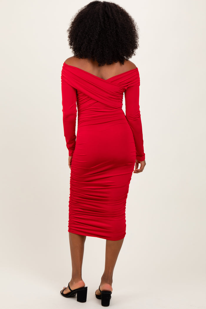 woman wearing a fitted red off-the-shoulder midi dress with ruching and long sleeves, seen from the back