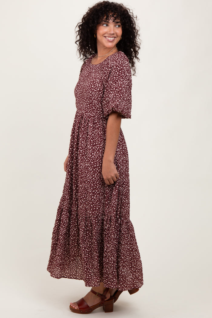 woman wearing a maroon floral maxi dress with puff sleeves and a tiered skirt