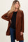 woman wearing a rust-colored maternity wrap coat with a black top and showing her baby bump