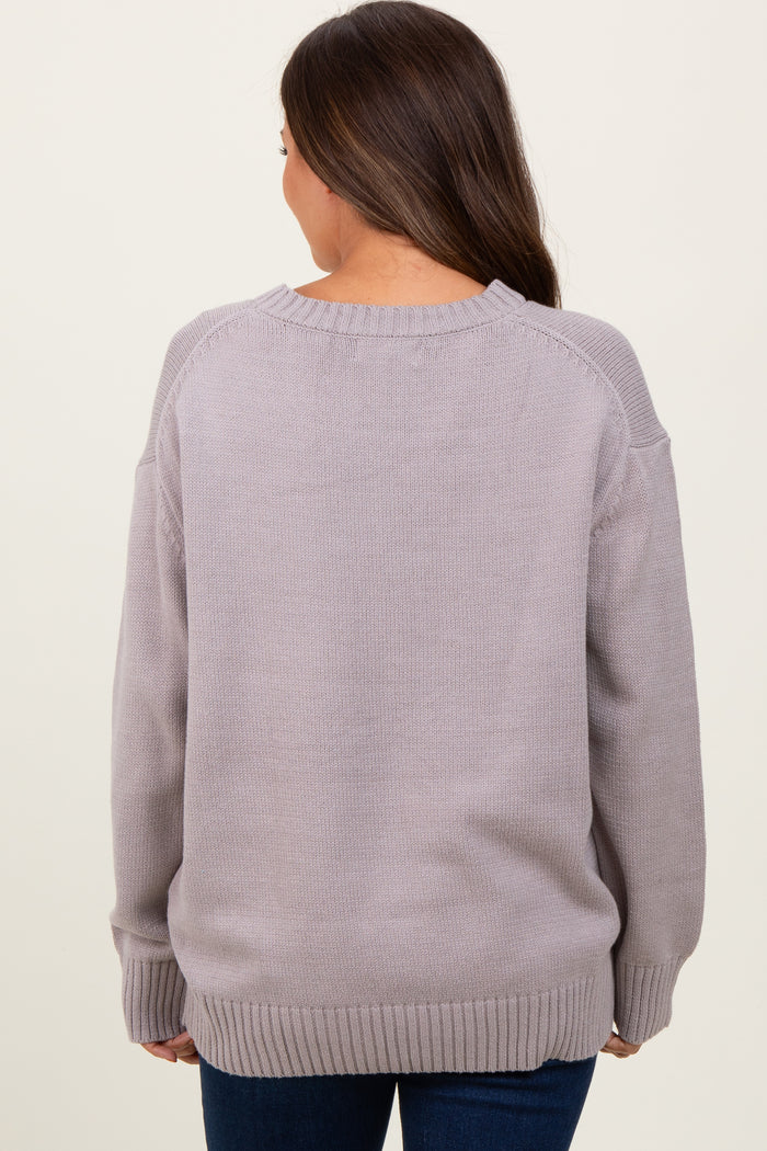 woman wearing a light gray oversized maternity sweater with a round neckline and ribbed cuffs, seen from the back