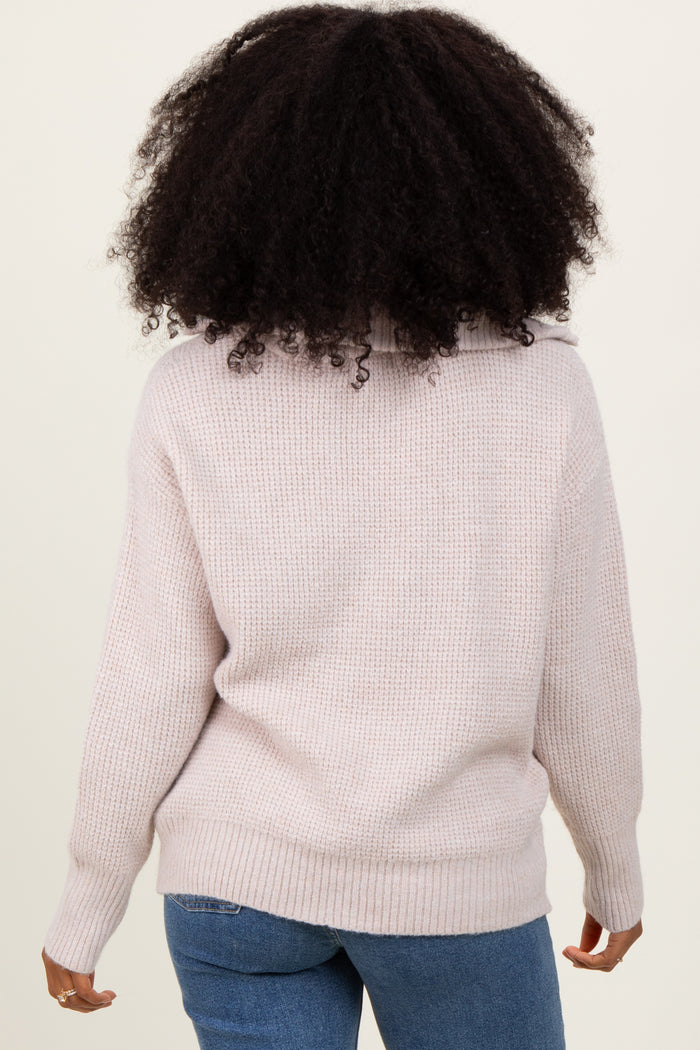 woman wearing a light pink oversized knit sweater with a cozy turtleneck and cuffed sleeves
