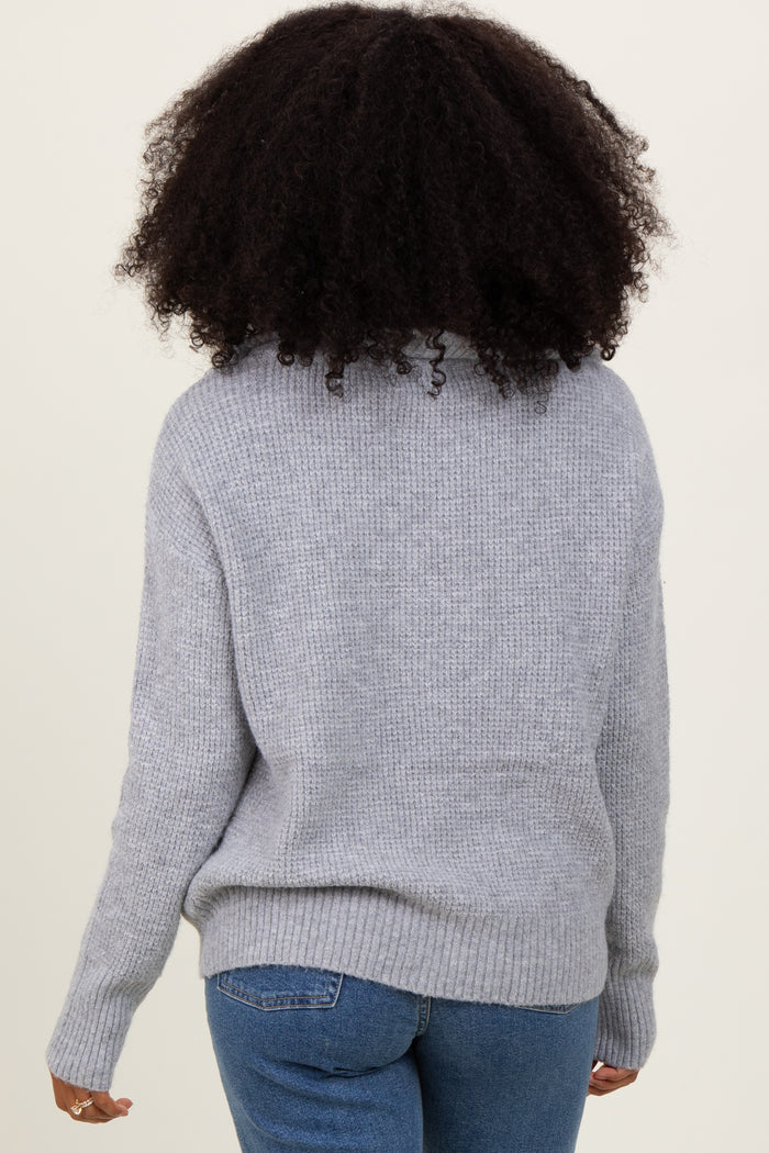 woman wearing a cozy gray knitted sweater with a relaxed fit and ribbed hem, viewed from the back