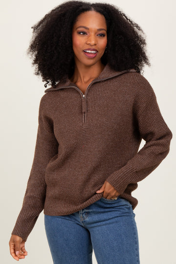 woman wearing a brown quarter-zip sweater with a textured knit and loose fit paired with blue jeans