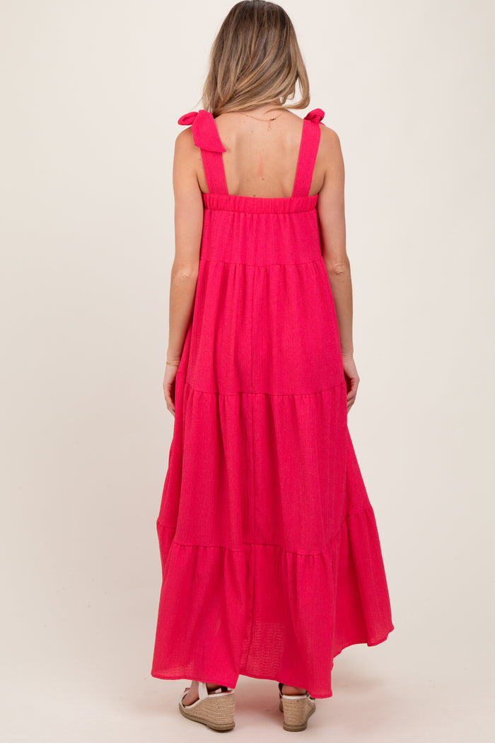 woman wearing a hot pink tiered maxi maternity dress with bow straps, showing a relaxed fit and flowy silhouette