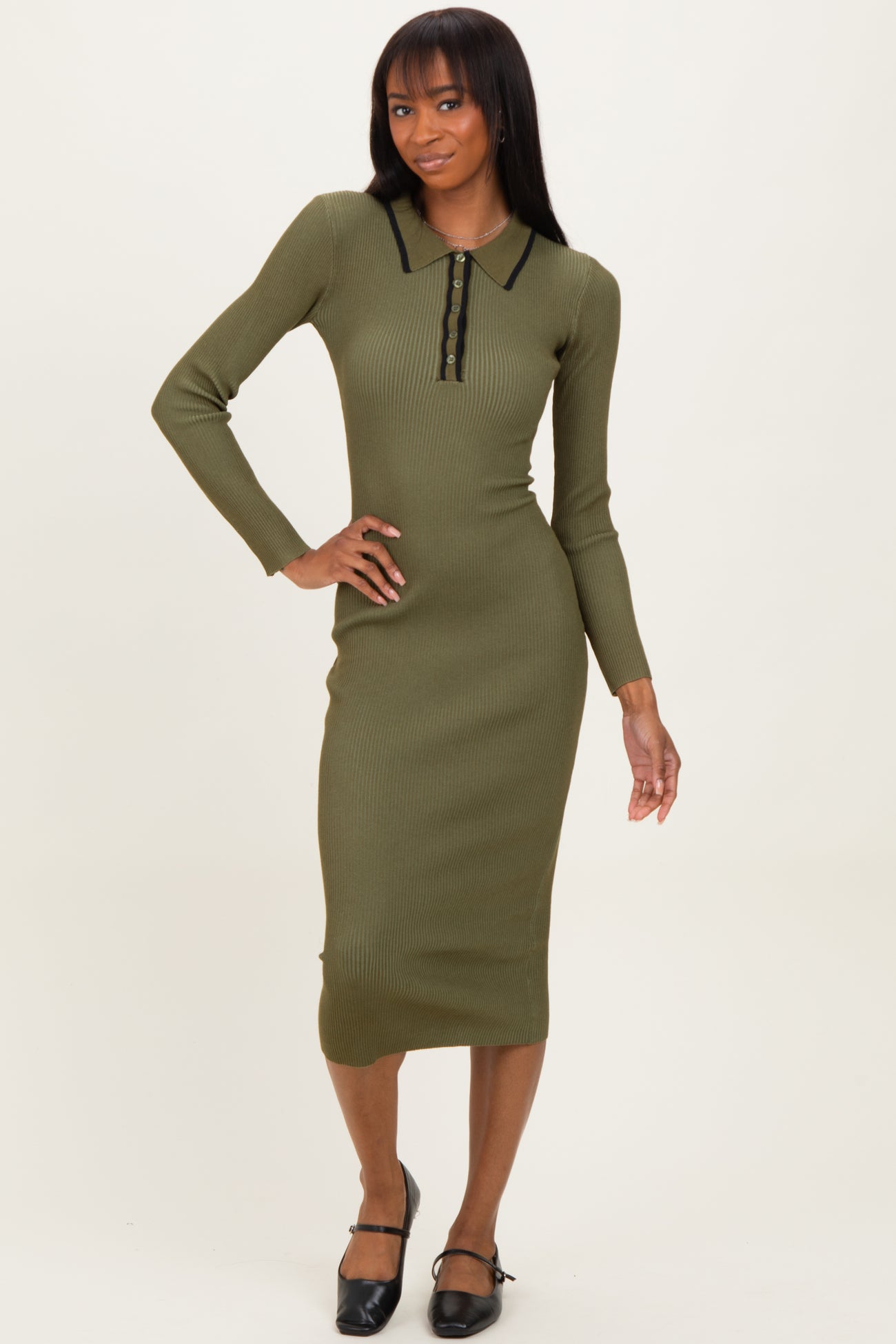 woman wearing an olive green ribbed midi dress with a collar and button detailing, posing with one hand on her hip