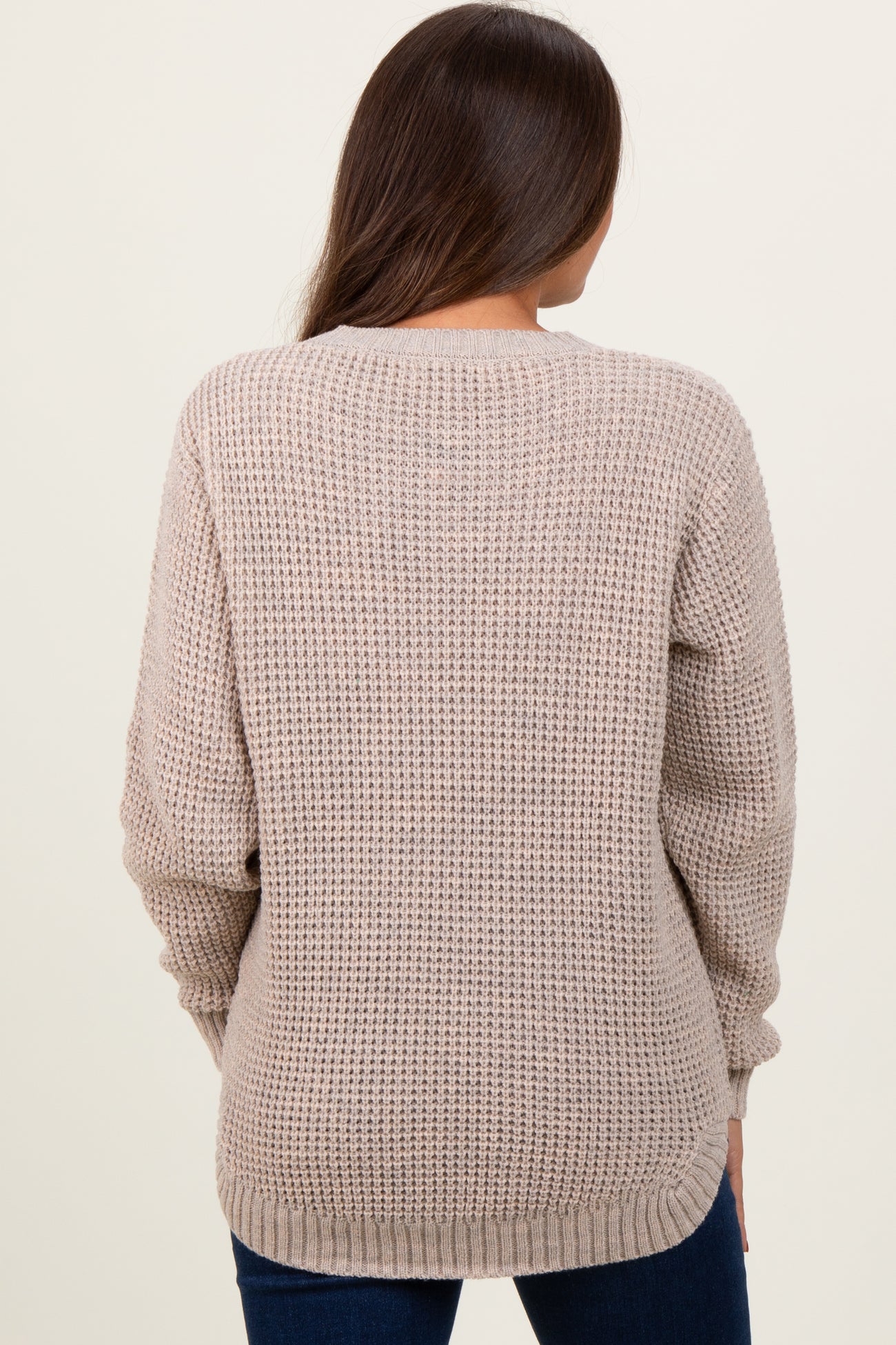woman wearing a light beige knit maternity sweater from the back with long sleeves and a relaxed fit