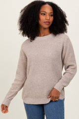 woman wearing a beige knit sweater with a relaxed fit and long sleeves, paired with blue jeans