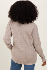 woman wearing a beige oversized knit sweater from the back, paired with light blue jeans