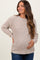 woman wearing a beige knit maternity sweater and holding her baby bump