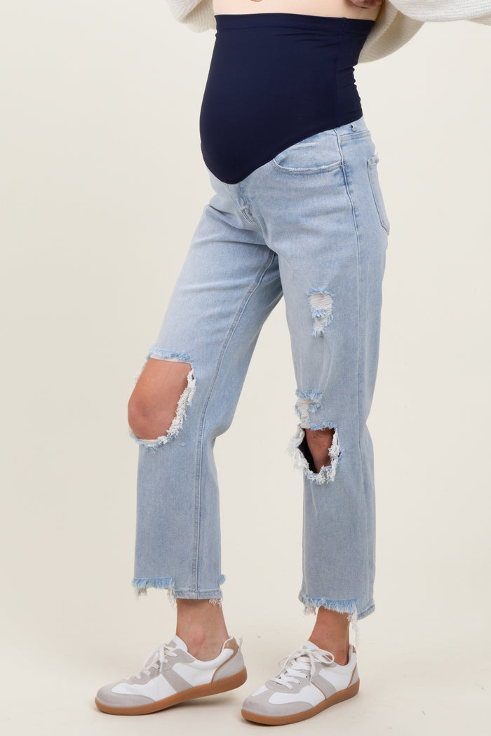 woman wearing a navy blue maternity belly band with distressed light blue maternity jeans and gray sneakers