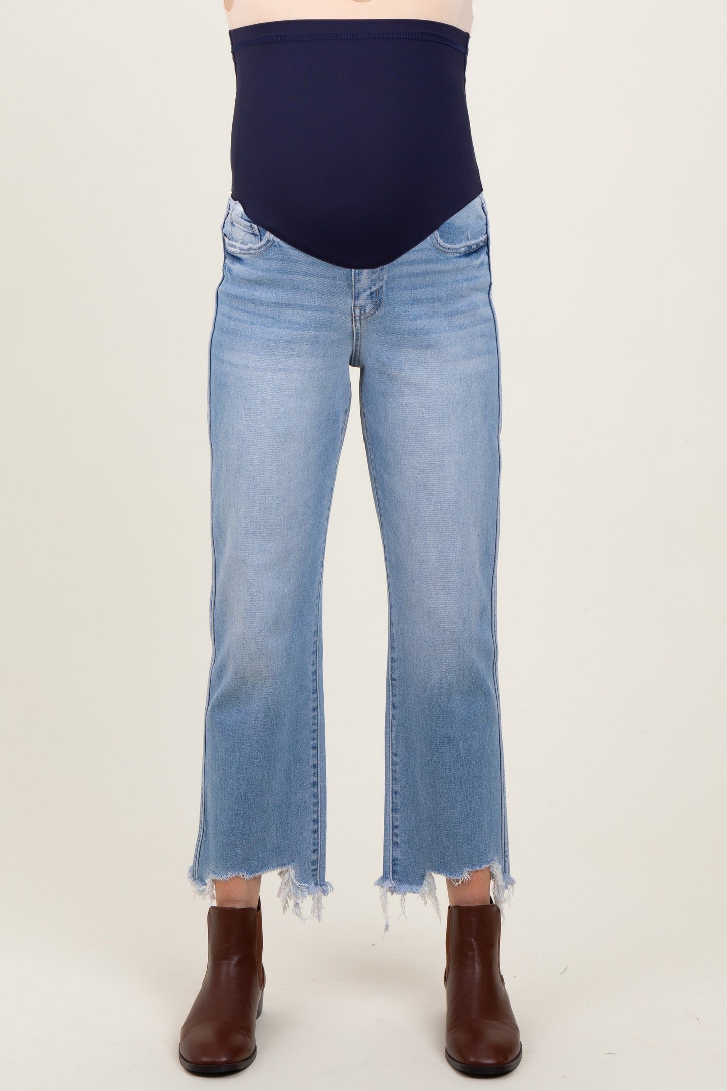 woman wearing light wash maternity jeans with a frayed hem and a navy stretchy maternity panel