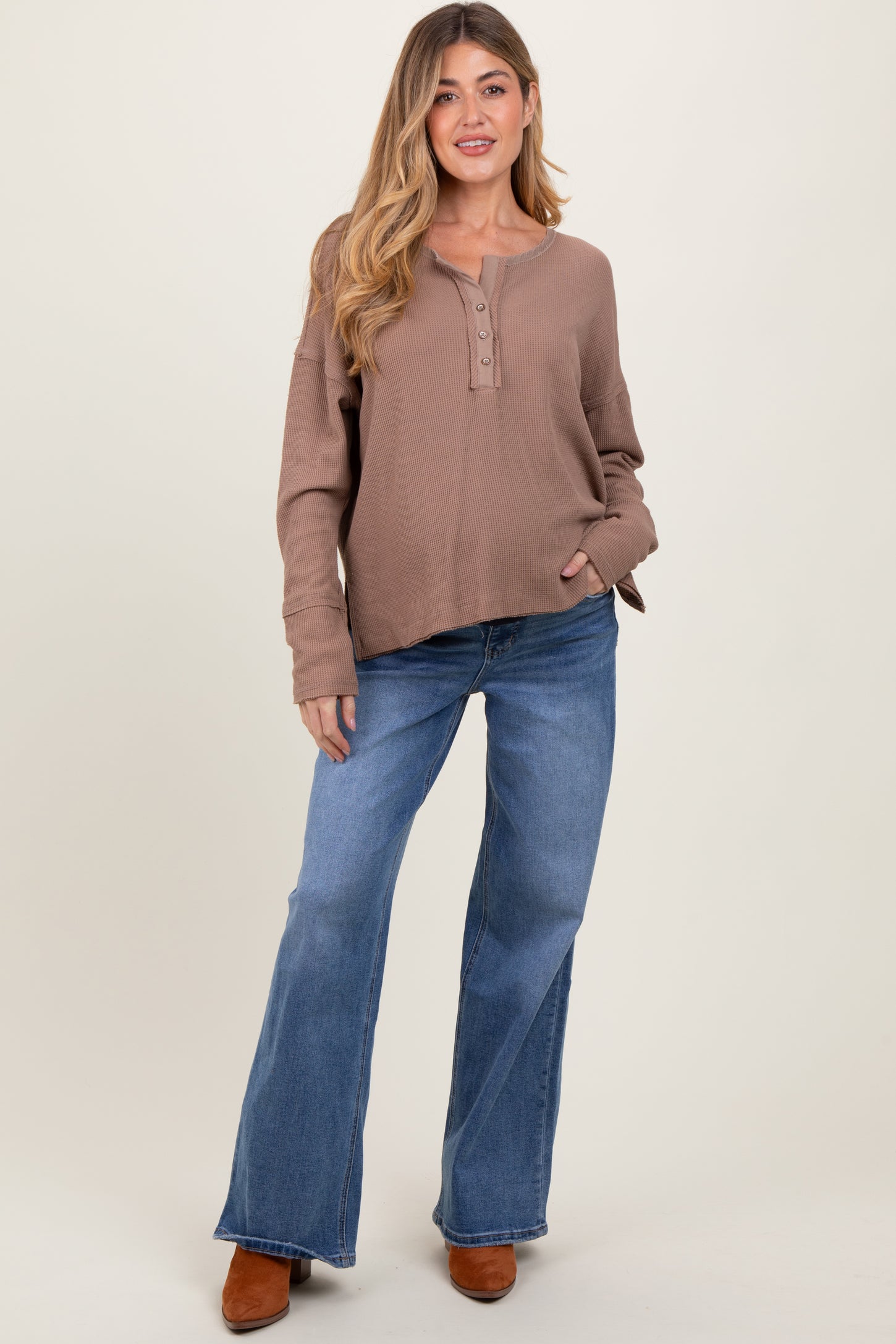 woman wearing a brown ribbed maternity top with buttons and blue flared jeans