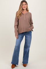 woman wearing a brown ribbed maternity top with buttons and blue flared jeans