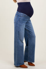 woman wearing a pair of blue wide-leg maternity jeans with a supportive waistband, showcasing her baby bump.