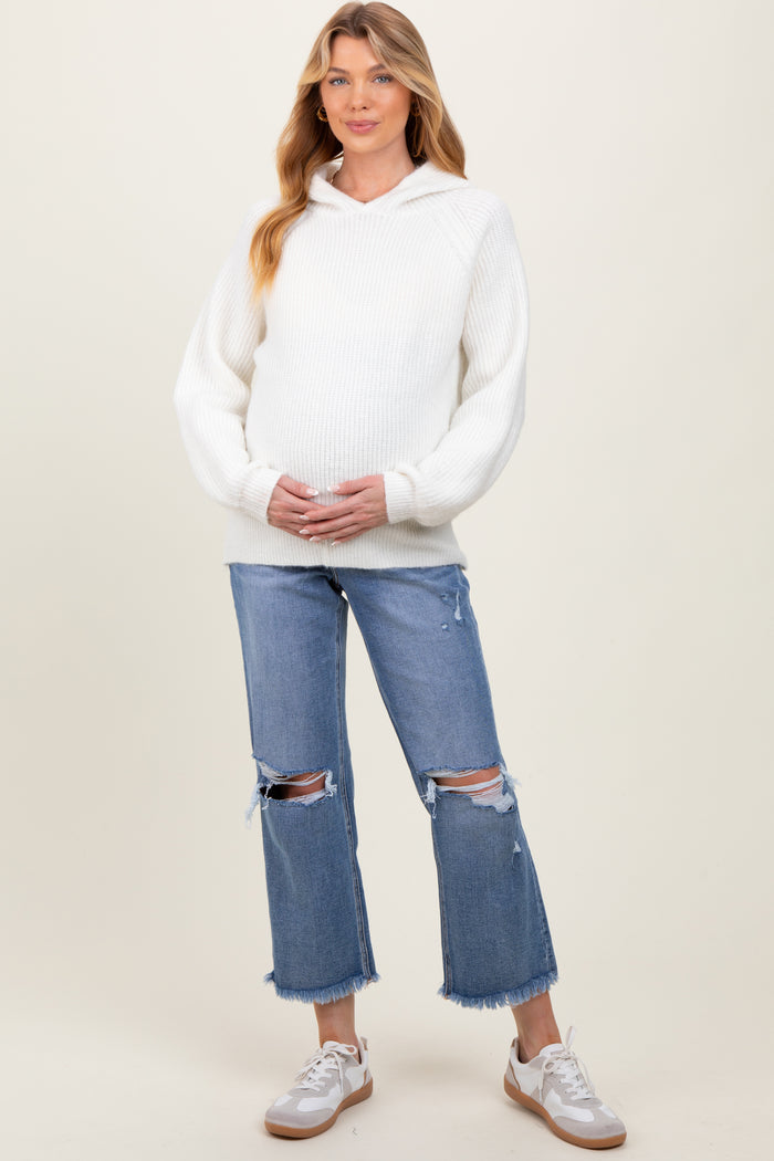 woman wearing a white ribbed maternity hoodie and distressed light wash jeans, holding her baby bump