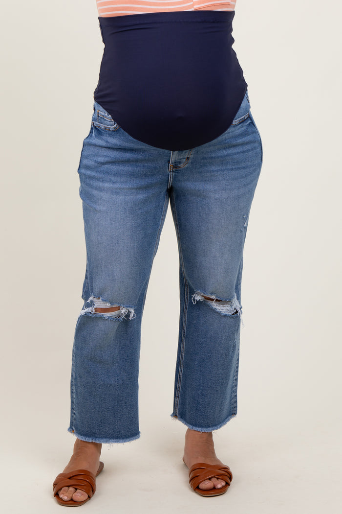woman wearing distressed blue maternity jeans with a dark blue belly panel and a visible baby bump