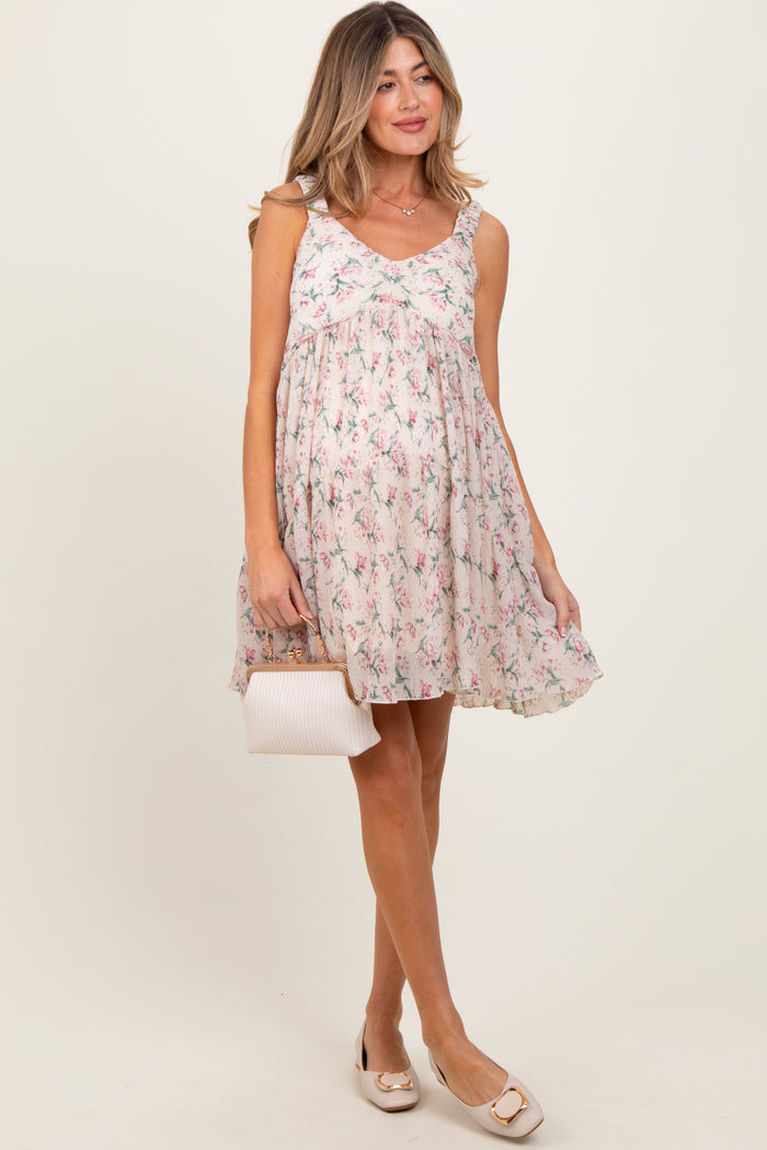 woman wearing a floral print maternity dress with spaghetti straps and a flowy fit, holding a small handbag