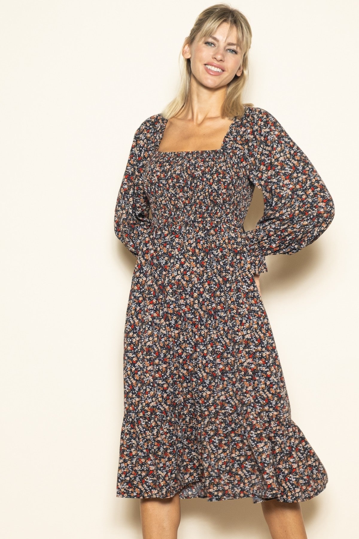 woman wearing a dark floral midi dress with puff sleeves and a smocked bodice