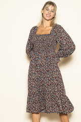 woman wearing a dark floral midi dress with puff sleeves and a smocked bodice