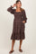 woman wearing a black floral maternity dress with a square neckline, puff sleeves, and pockets, showcasing baby bump