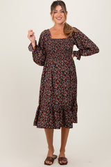 woman wearing a black floral maternity dress with long sleeves and a ruffled hem