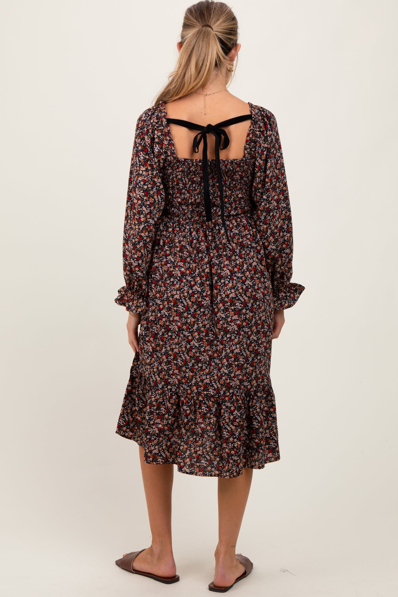 woman wearing a dark floral maternity dress with a tied back and ruffled hem