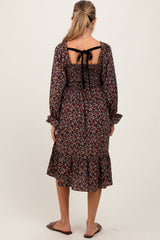 woman wearing a dark floral maternity dress with a tied back and ruffled hem