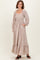 woman wearing a cream floral maxi dress with long puff sleeves and pockets, standing against a neutral background