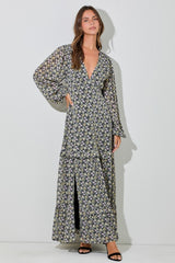 woman wearing a black floral maxi dress with a v-neckline, long sleeves, and a front slit.