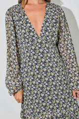 woman wearing a black floral long sleeve dress with a deep v-neck and loose, flowing sleeves