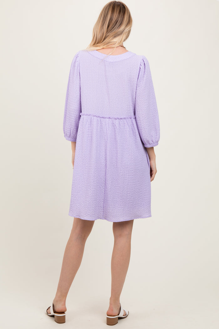 woman wearing a lavender puff sleeve dress with a cinched waist, shown from the back