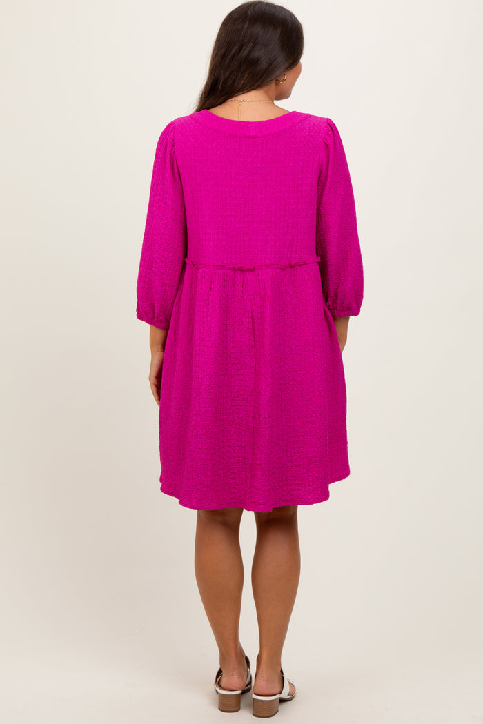 woman wearing a bright pink maternity dress with three-quarter sleeves and a gathered waist, seen from the back