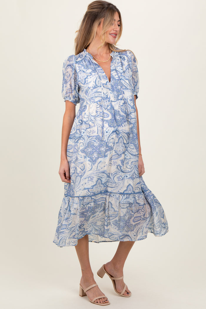 woman wearing a blue and white paisley print maternity dress with puff sleeves and a tiered skirt