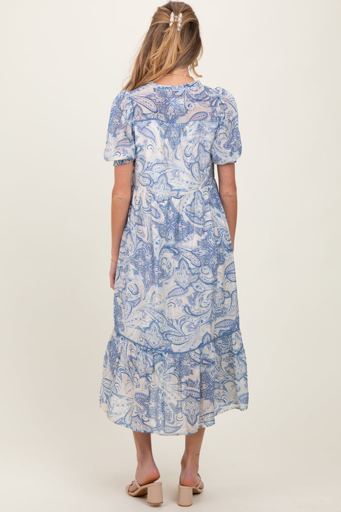 woman wearing a blue paisley print maternity dress with short sleeves and a tiered skirt, seen from the back
