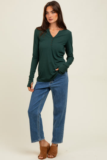 woman wearing a dark green long sleeve henley top with a button detail and blue high-waisted jeans