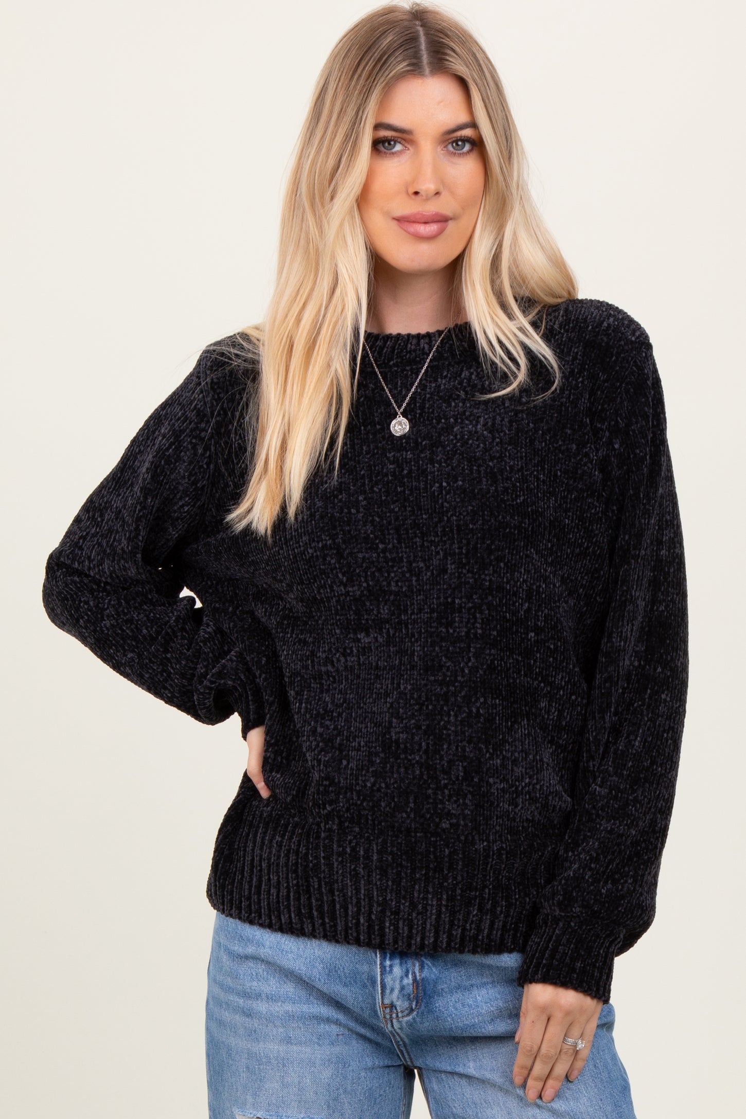 woman wearing a black textured knit sweater paired with light blue high-waisted jeans