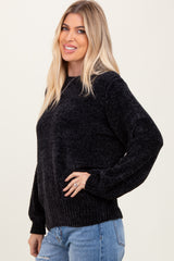 woman wearing a black textured knit sweater with balloon sleeves and a relaxed fit paired with blue jeans