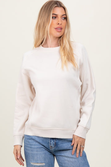 woman wearing a cream long sleeve sweatshirt with ribbed cuffs and a relaxed fit, paired with blue jeans