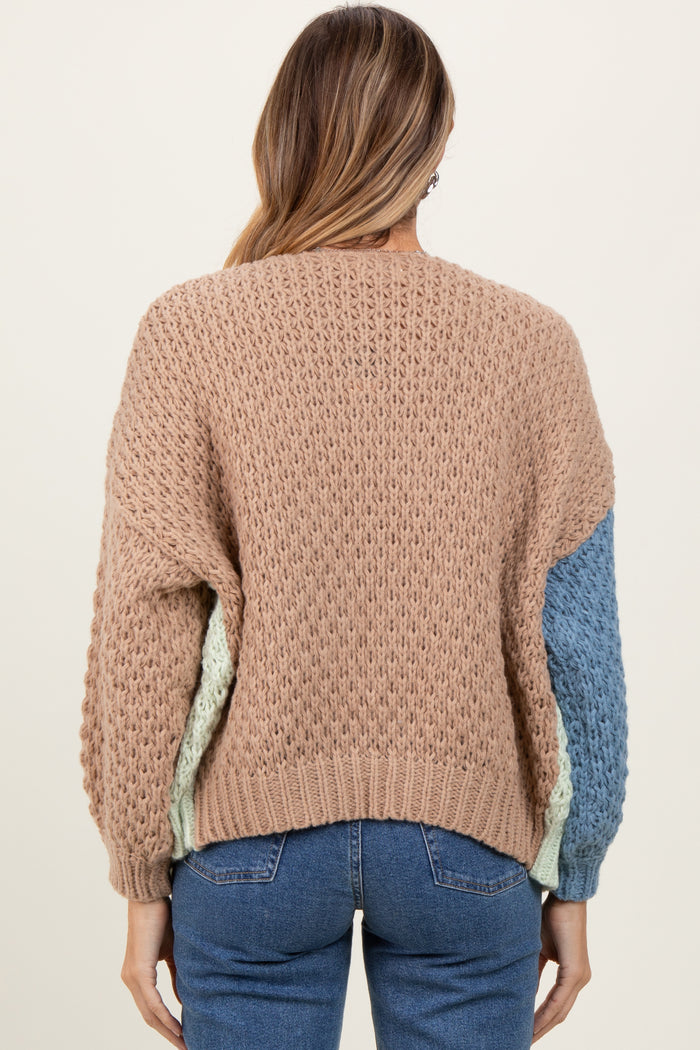 woman wearing a pastel color block knit sweater with a textured pattern and long sleeves, facing away from the camera