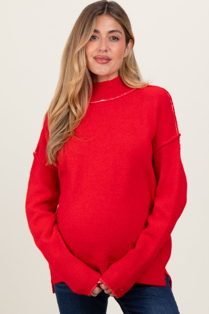 woman wearing a red oversized maternity sweater with a mock neck and visible baby bump