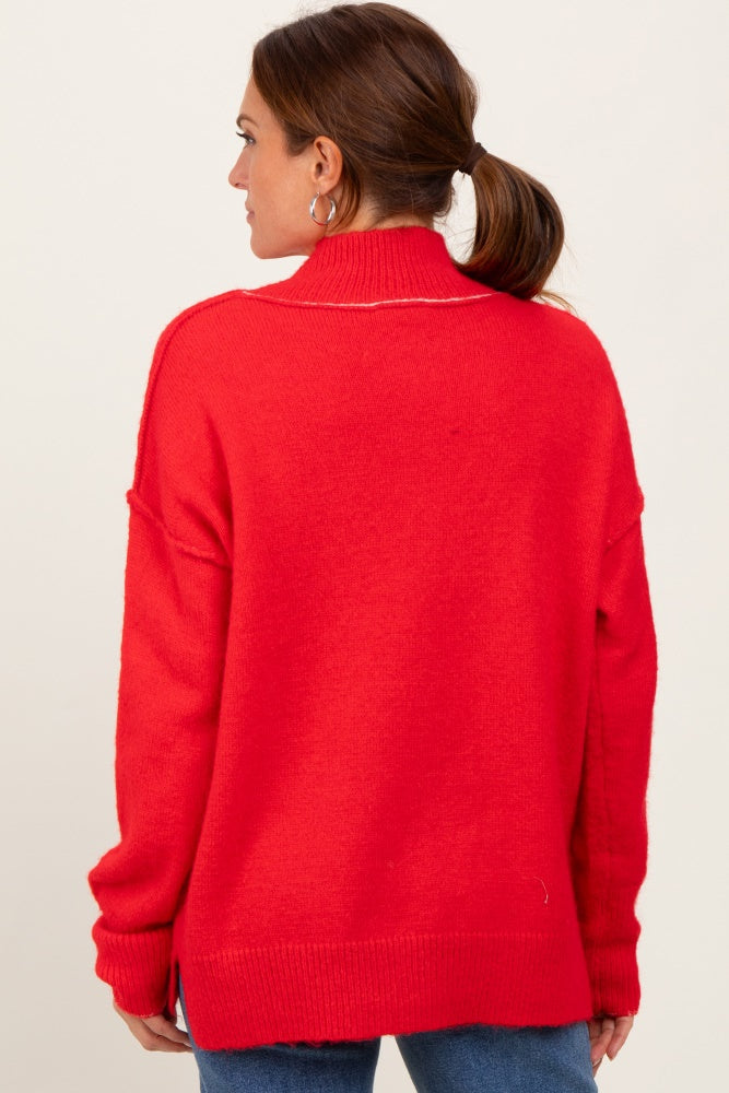 woman wearing a bright red oversized pullover sweater with a high collar and relaxed fit, viewed from the back