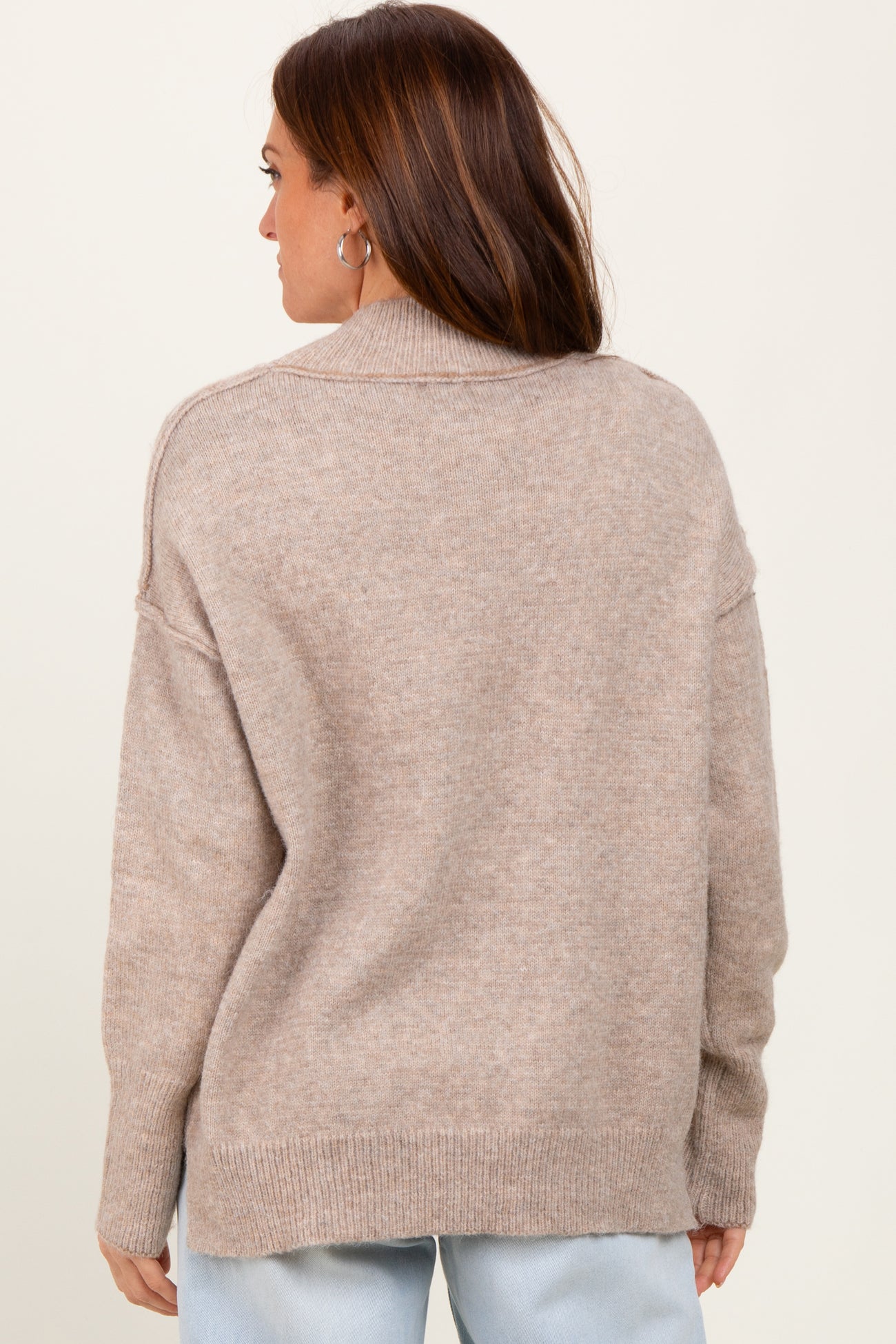 woman wearing a beige oversized knit sweater with a relaxed fit and ribbed hem, shown from the back