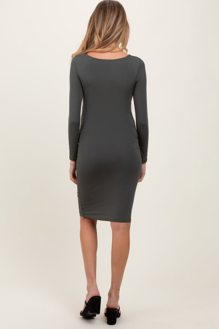 woman wearing a dark green long sleeve maternity dress, viewed from the back, fitted style
