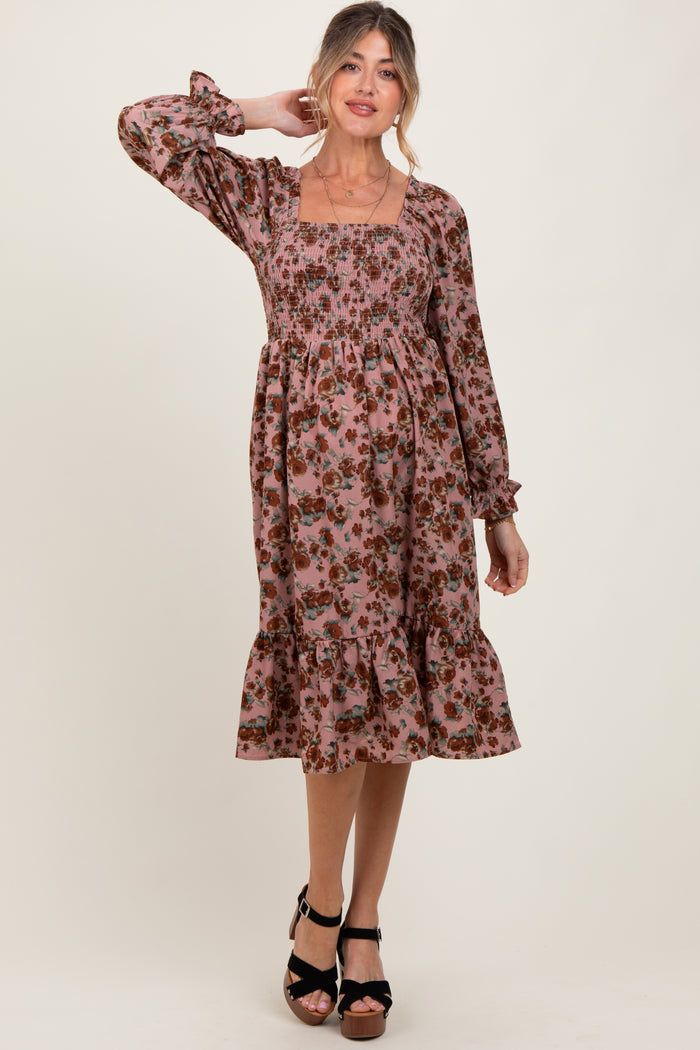 woman wearing a floral pink maternity dress with long sleeves and a tiered ruffle hem, showcasing a baby bump