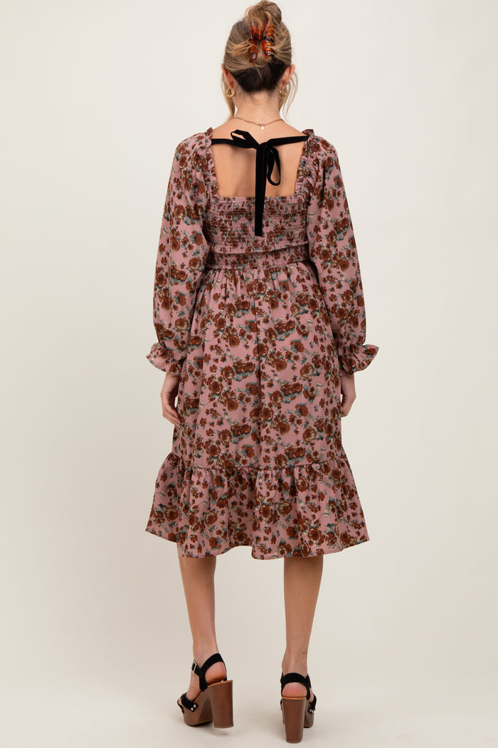 woman wearing a floral maternity dress with a smocked back and tie detail, featuring long sleeves and a ruffled hem