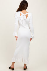 woman wearing a white ribbed long sleeve dress with a bow detail at the back and ruffle hemline