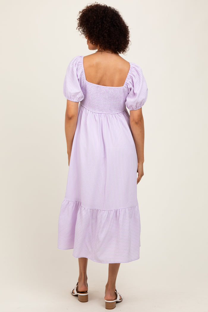 woman wearing a lavender striped midi dress with puff sleeves and a gathered back detail